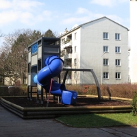 Blaue Röhrenrutsche an hohem silbernen Spielturm