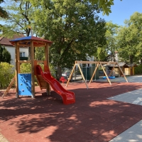 Große Schaukelkombination mit Nestschaukel und Spielturm mit Kletterwand auf rotem Fallschutz