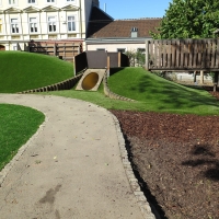 Hügeliger Kinderspielplatz mit Spielturm in der Schule