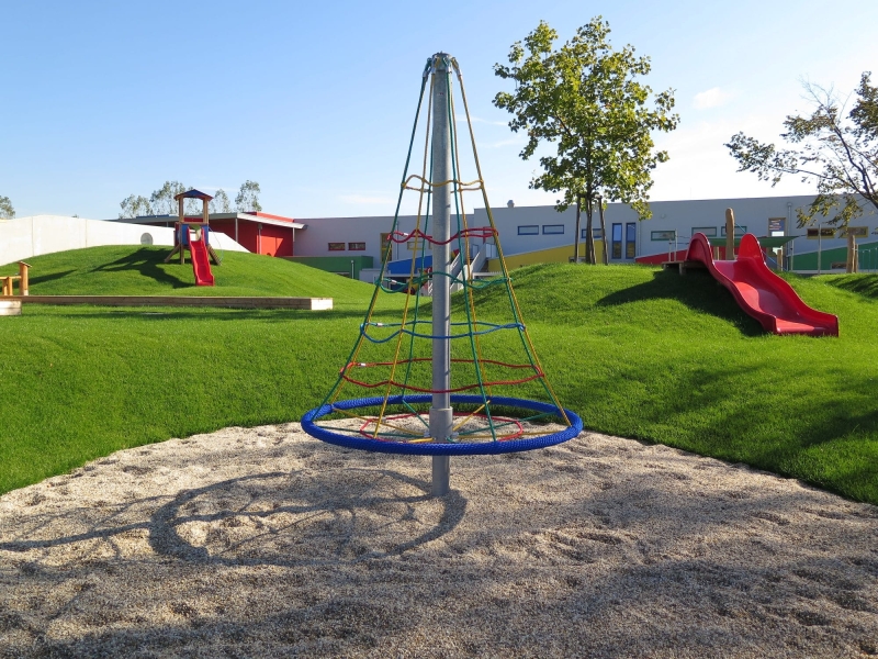 Karussellturm mit Kletterseilen auf Kiessand und grünem Rasen