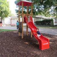 Rutschenturm mit spielendem Kind auf der roten Rutsche