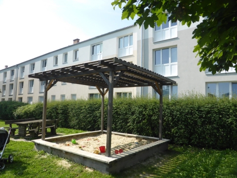 Schattenpergola über Sandkasten aus Holz in Wohnanlage