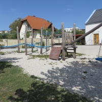 Spielplatz aus Holz mit Nestschaukel am Pendel und Kletterwand