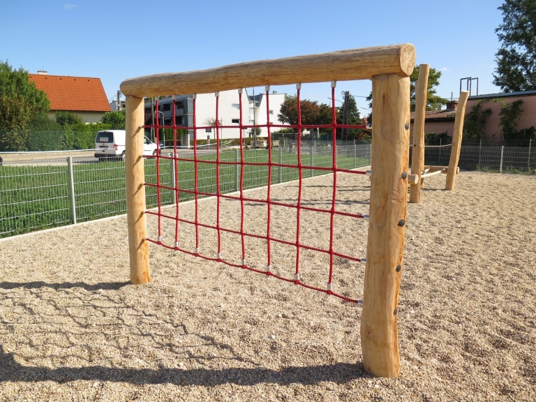 Kletternetzwand von FREISPIEL an Holzpalisaden auf Spielplatz