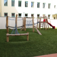 Kinderspielplatz mit viel Holz, Netze zum balancieren und roter Rutsche