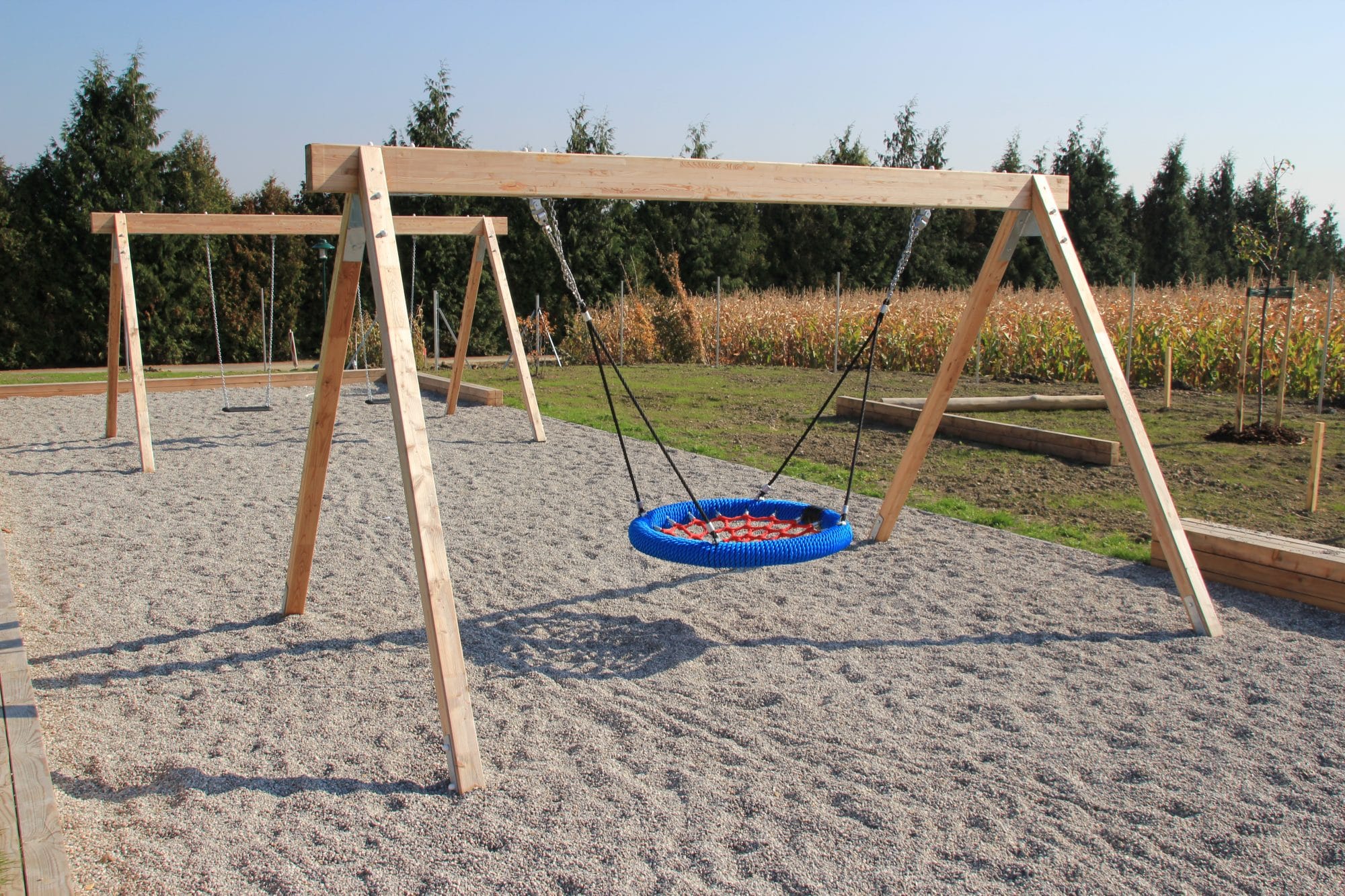 Nestschaukel an Holzgestell im Kies in blau und rot