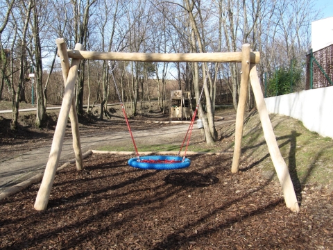 Nestschaukel an Naturholzbalken auf Rindenmulch für Kinder im Park