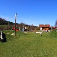 Spielplatz im Grünen mit verschiedenen Spielgeräten wie Hangschaukel