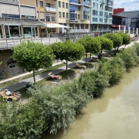 Uferpromenade mit Holzliegen am Wasser in der Stadt