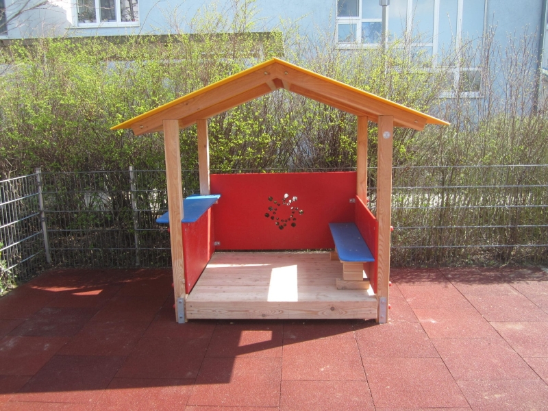 Spielhaus aus Holz mit roten Paneelen und gelbem Dach von FREISPIEL